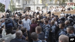 WBC Heavyweight Champion Vitali Klitschko, center in white t-shirt, talks to riot police at an opposition protest rally in front of the Ukrainian House in central Kiev, Ukraine, July 4, 2012.