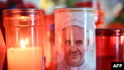 Candles are lit at the statue of John Paul II outside the Gemelli University Hospital where Pope Francis is hospitalized with pneumonia, in Rome, March 4, 2025.