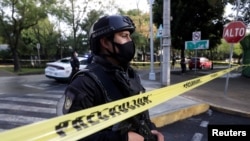 A police officer stands behind a cordon tape at an area where a shooting took place in Mexico City, Mexico, June 26, 2020.