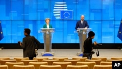 Photographers move around in a nearly empty press room as European Council President Charles Michel, right, and European Commission President Ursula von der Leyen, left, speak after a video-conference with G7 leaders at the European Council building…