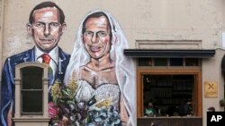 ພາບວາດທີ່ສະແດງໃຫ້ເຫັນ ເຖິງອະດີດ ນາຍົກລັດຖະມົນຕີ Tony Abbott ທີ່ເປັນທັງເຈົ້າບ່າວ ແລະເຈົ້າສາວ ໃນຊຸດແຕ່ງ
ງານ ທີ່ຫ້ອຍໄວ້ໃນຝາຮ້ານກາເຟແຫ່ງນຶ່ງ ໃນນະຄອນ Sydney, 12 ກັນຍາ, 2017. 