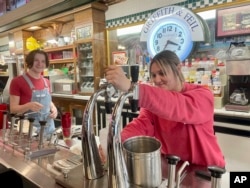 Malli Jarrett, right, serves up drinks from the soda fountain while co-worker Nathaniel Fornash watches at Griffith & Feil Drug on Thursday, March 30, 2023, in Kenova, W. Va. (AP Photo/John Raby)