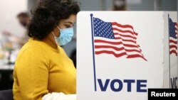 FILE - A woman fills in a ballot for the 2020 U.S presidential election in Fairfax, Virginia, Nov. 3, 2020. 