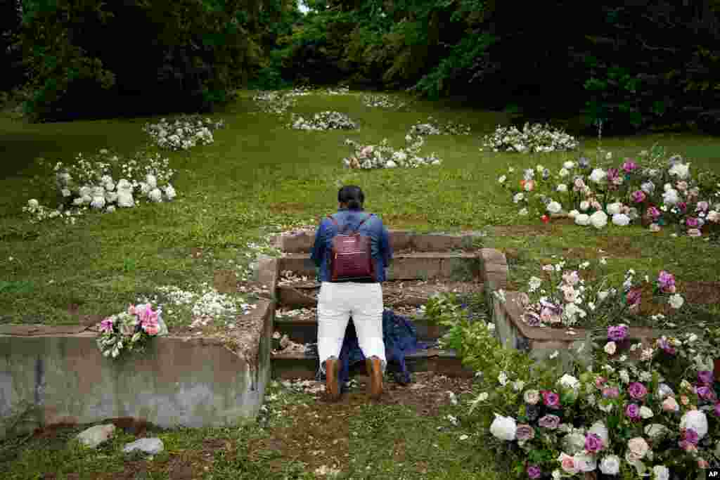 Linda Porter of Birmingham, Ala., kneels at a makeshift memorial of flowers for the Tulsa Race Massacre near the historic Greenwood district during centennial commemorations of the massacre, in Tulsa, Oklahoma.