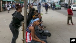 Un pasajero lleva una camiseta con la bandera de Estados Unidos en una parada de autobús en La Habana, Cuba, el miércoles 15 de enero de 2025. (Foto AP/Ariel Ley).