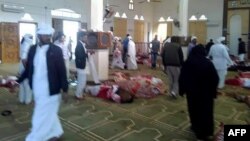 WARNING: Graphic content - Egyptians walk past bodies following a gun and bombing attack at the Rawda mosque, roughly 40 km west of North Sinai capital of El-Arish, on Nov. 24, 2017.