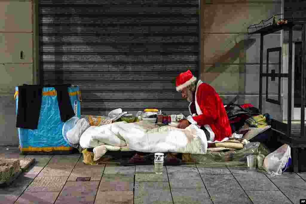 A homeless man, name given Rafael, wears a Santa Claus outfit as he prepares to have dinner by the side of a road, in Milan, Italy.