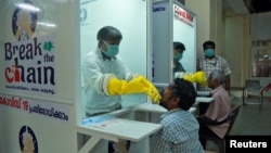 Medical staff members of a government-run medical college collect swabs from people to test for coronavirus disease (COVID-19) at a newly installed Walk-In Sample Kiosk in Ernakulam in the southern state of Kerala, India, April 6, 2020.
