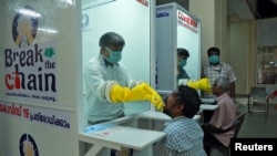 印度南部喀拉拉邦额尔纳库拉姆，一所公办医学院的医护人员在新安装的步入式样本亭，从人们身上采集拭子进行冠状病毒病(COVID-19)检测。（2020年4月6日）