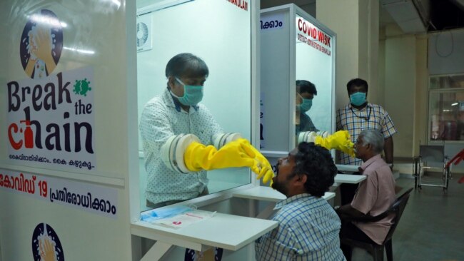 印度南部喀拉拉邦额尔纳库拉姆，一所公办医学院的医护人员在新安装的步入式样本亭，从人们身上采集拭子进行冠状病毒病(COVID-19)检测。（2020年4月6日）