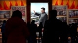 Visitors walk in front of a picture of China's President Xi Jinping at the Museum of the Communist Party of China in Beijing on November 11, 2021.