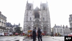 Polisi berjaga sementara para petugas pemadam kebakaran memadamkan api di Katedral Santo Pierre-dan-Santo Paul di Nantes, barat Perancis, 18 Juli 2020. 