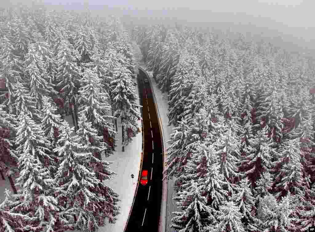 A car drives between snow-covered trees in the Taunus region near Frankfurt, Germany.
