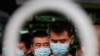 Commuters wearing protective face masks to help curb the spread of the coronavirus line up to board a bus at a terminal in Beijing, June 22, 2020.