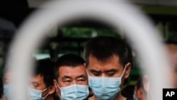 Commuters wearing protective face masks to help curb the spread of the coronavirus line up to board a bus at a terminal in Beijing, June 22, 2020.