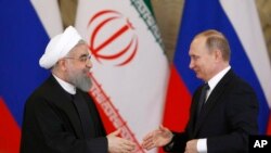 Russian President Vladimir Putin, right, shakes hands with Iranian President Hassan Rouhani during a joint news conference at the Kremlin in Moscow, Russia, Tuesday, March 28, 2017. 