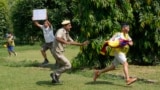 An Indian policeman runs after an exile Tibetan during a protest to coincide China marking its 75th year of Communist Party rule, outside Chinese embassy, in New Delhi, Oct. 1, 2024. 