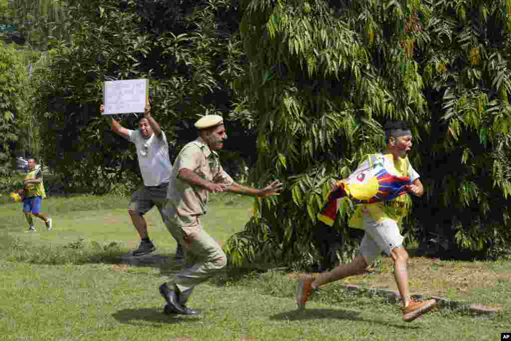 An Indian policeman runs after an exile Tibetan during a protest against human rights situation in Tibet, outside Chinese embassy, in New Delhi.