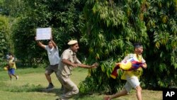 An Indian policeman runs after an exile Tibetan during a protest against human rights situation in Tibet, outside Chinese embassy, in New Delhi.