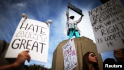 FILE - Protesters hold up signs during a march and rally against the election of Republican Donald Trump as president of the United States in Los Angeles, California, Nov. 12, 2016.