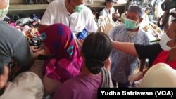 Pedagang pasar dan kuli gendong mengantri untuk mendapatkan hand sanitizer gratis dari komunitas warga Tionghoa di pasar tradisional Solo, 21 Maret 2020. (Foto: VOA/ Yudha Satriawan)