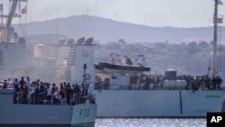 FILE - Migrants arrive in Porto Empedocle, Sicily, aboard two military ships after being transferred from the island of Lampedusa, where a number of small boats carrying migrants arrived a few days earlier, July 27, 2020. 