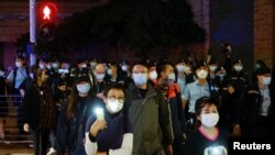 Grupos de simpatizantes encienden sus teléfonos celulares mientras 47 activistas prodemocracia acusados bajo la Ley de Seguridad Nacional son trasladados de una corte de Hong Kong el 4 de marzo de 2021.