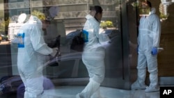 Police investigators are seen through a plate glass window as they prepare to conduct forensic analysis in the apartment where prosecutor Laberto Nisman lived and was found dead almost a month ago, in Buenos Aires, Argentina, Feb. 13, 2015.