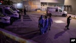 Health workers check on their mobile phones as they stand outside Veracruz General Hospital after a strong earthquake, in Veracruz, Mexico, Sept. 7, 2021. 