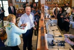 President Joe Biden hands ice cream to Sen. Tammy Baldwin, D-Wis., during a stop at The Pearl Ice Cream Parlor, June 29, 2021, in La Crosse, Wis.