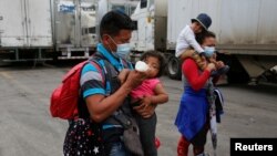 Un migrante hondureño que intentaba llegar a Estados Unidos alimenta a un niño mientras las autoridades guatemaltecas envían a los migrantes de regreso, en la frontera de El Florido entre Guatemala y Honduras, en Chiquimula, el 19 de enero de 2021.