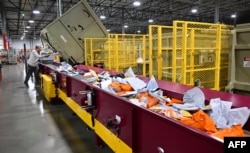 FILE - Seorang karyawan Layanan Pos Amerika Serikat (USPS) di Los Angeles memilah surat di Pusat Pemrosesan dan Distribusi surat menjelang musim liburan, 30 November 2022. (Frederic J. BROWN / AFP)