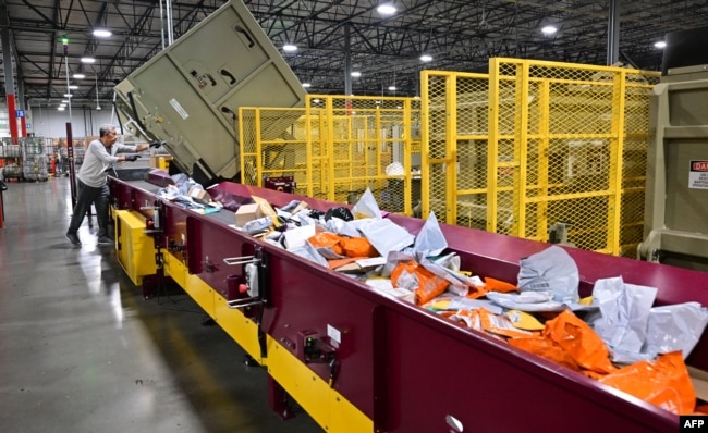 FILE - Seorang karyawan Layanan Pos Amerika Serikat (USPS) di Los Angeles memilah surat di Pusat Pemrosesan dan Distribusi surat menjelang musim liburan, 30 November 2022. (Frederic J. BROWN / AFP)