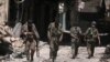 FILE - Syria Democratic Forces (SDF) fighters walk on the rubble of damaged shops and buildings in the city of Manbij, in Aleppo Governorate, Syria, Aug. 10, 2016.