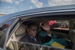 FILE - Cameroonian opposition leader Maurice Kamto (L) sits in the back of a car as he is driven away on Oct 5, 2019, the day of his release from prison in Yaounde.