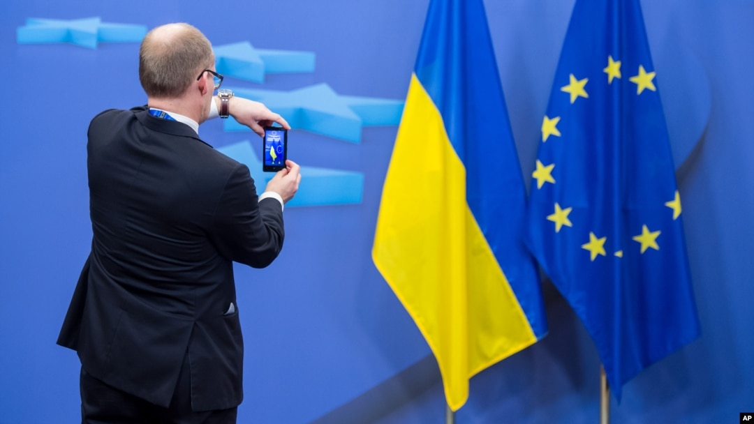 A member of a delegation takes a photo with his cellphone of the Ukrainian and EU flags after an EU summit in Brussels, March 6, 2014.