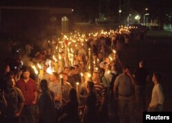 FILE - White nationalists carry torches on the grounds of the University of Virginia, on the eve of a "Unite the Right" rally in Charlottesville, Virginia, Aug. 11, 2017.