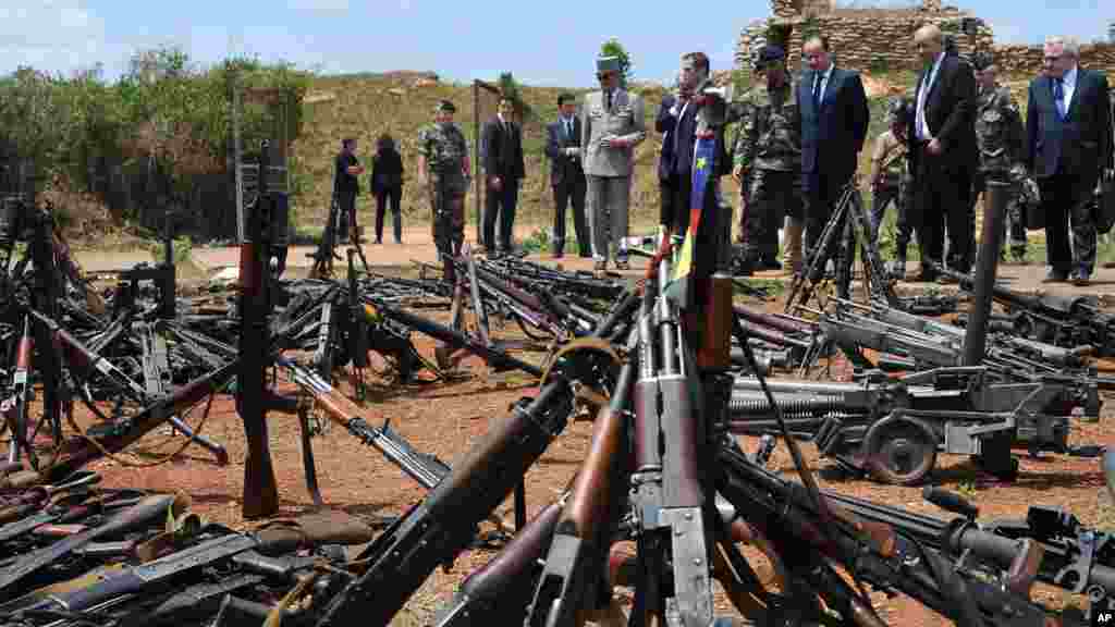 Le président français François Hollande, troisième à droite, et son ministre de la Défense Jean-Yves Le Drian, deuxième à droite, passent en revue des armes confisquées aux ex-rebelles Séléka et les milices anti-alaka par les militaires français de l&#39;opération Sangaris, dans une base militaire française à Bangui, en République centrafricaine, l28 février 2014. (AP photo / Sia Kambou, Pool)