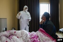 A doctor (L) talks with a patient during his rounds at the ward of a quarantine zone in Wuhan, the epicenter of the new coronavirus outbreak, in China’s central Hubei province, Feb. 3, 2020.