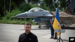 Президент України Володимир Зеленський виступає на тлі винищувачів F-16 ЗСУ в невідомому місці в Україні, 4 серпня 2024 р. (Фото: AP Photo/Єфрем Лукацький)