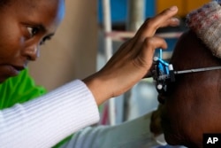 An optometry student, carries out an eye test on a patient for a new pair of glasses to be made, outside the Phelophepa eye clinic carriage in Tembisa, east of Johannesburg, South Africa, Thursday, Aug. 22, 2024. (AP Photo/Themba Hadebe)