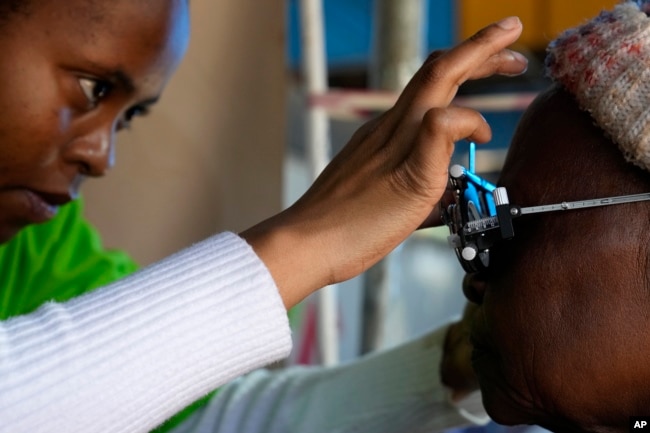 An optometry student, carries out an eye test on a patient for a new pair of glasses to be made, outside the Phelophepa eye clinic carriage in Tembisa, east of Johannesburg, South Africa, Thursday, Aug. 22, 2024. (AP Photo/Themba Hadebe)