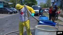 Un miembro de la Cruz Roja llena tanques con agua para los residentes de la colonia Los Almendros, en Ciudad Delgado, El Salvador, como parte del esfuerzo para prevenir un mayor contagio del nuevo coronavirus, el 8 de abril de 2020.