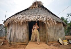 A young woman from the Uru Eu Wau Wau tribe leaves a straw-thatched hut in the tribe's reserve in the Amazon, south of Porto Velho, Brazil, Aug. 29, 2019.