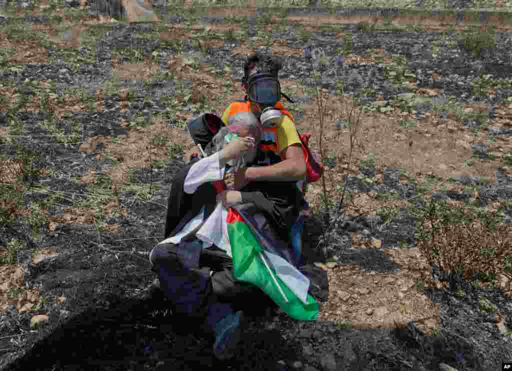 A paramedic helps a priest, suffering from teargas after Israeli border police dispersed Palestinian protesters in a rally against the American-led Mideast peace conference, near the settlement of Beit El, at the outskirts of the West Bank. 