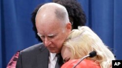 Gubernur California Jerry Brown (kiri) dipeluk oleh Holly Dias, seorang pekerja di restoran waralaba "Burger King" yang memuji keputusan upah minimum $15/jam di sana (foto: dok).