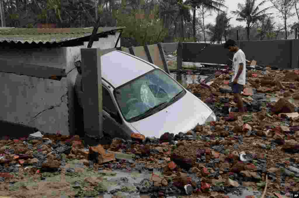 A man looks at a car damaged by Cyclone Yaas that made a landfall at Digha on the Bay of Bengal coast, West Bengal state, India.