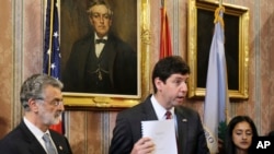 U.S. Attorney Steven Dettelbach, center, holds up the settlement agreement with the City of Cleveland a news conference, May 26, 2015, in Cleveland.