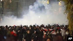 Demonstrators run away from a cloud of tear gas during a rally against the government's decision to suspend negotiations on joining the European Union for four years in Tbilisi, Georgia, Dec. 2, 2024.