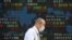 A man walks by an electronic stock board of a securities firm in Tokyo, Wednesday, Oct. 21, 2020. Asian shares mostly rose Wednesday, cheered by the gains on Wall Street as investors welcomed a batch of solid earnings reports from U.S. companies.(AP…